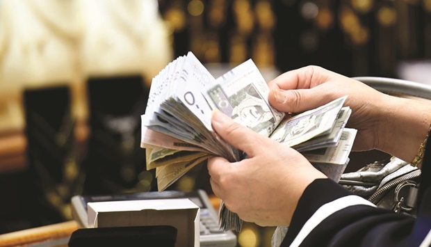 A Saudi woman counts banknotes as she makes a purchase at a jewellery shop in the Tiba gold market in the capital Riyadh (file). Non-oil gross domestic product u2013 the engine of job creation u2013 gained 5% while the oil economy grew 10.8%, according to preliminary estimates released by the General Authority for Statistics on Thursday.