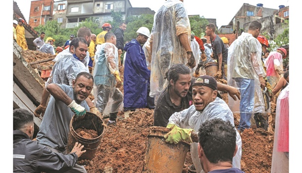 Residents help firefighters remove mud in search of victims after a landslide yesterday caused by heavy rains buried homes in Franco da Rocha, Sao Paulo state, Brazil.