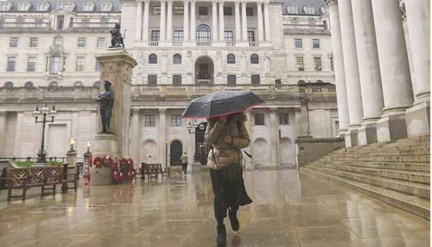 A pedestrian walks past the Bank of England in the City of London. The BoE has begun talks with the UK Debt Management Office and the Treasury over how to handle active sales of bonds held in its quantitative easing portfolio, according an official with knowledge of the matter.