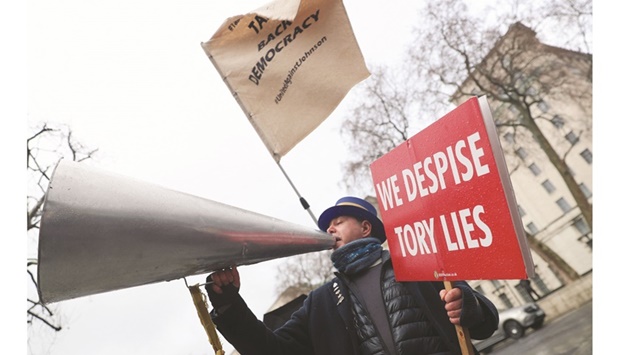 Steve Bray, a British activist, carries a sign and speaks into the megaphone as he participates in a protest against British Prime Minister Boris Johnson in London, yesterday.