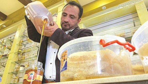 Vendor Abdullah Yarim pours honey into a glass bowl at his shop in Sanaa, Yemen.