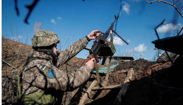 :A Ukrainian service member holds a machine gun in a trench at a position on the front line near the village of Travneve in Donetsk region, Ukraine February 21. REUTERS