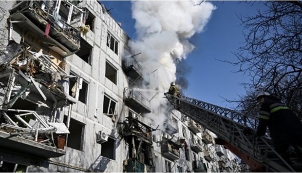 Firefighters work on a fire on a building after bombings on the eastern Ukraine town of Chuguiv on February 24, 2022, as Russian armed forces are trying to invade Ukraine from several directions, using rocket systems and helicopters to attack Ukrainian position in the south, the border guard service said.