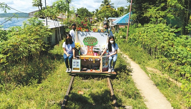 Student volunteers ride on their makeshift trolley which serves as a mobile library for children, in Tagkawayan, Quezon province, Philippines.