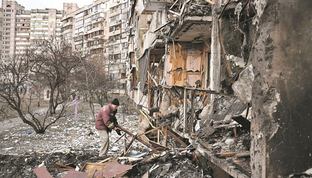 A man clears debris at a damaged residential building at Koshytsa Street, a suburb of the Ukrainian capital Kyiv, where a military shell allegedly hit yesterday.