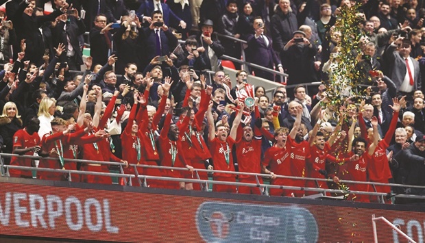 Liverpoolu2019s Jordan Henderson lifts the trophy as they celebrate winning the League Cup final against Chelsea at the Wembley Stadium in London yesterday. (Reuters)