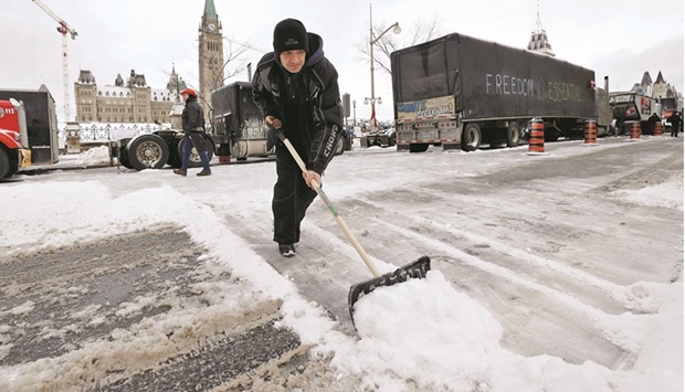 A demonstrator clears snow from the street as truckers and supporters continue to protest coronavirus (Covid-19) vaccine mandates in Ottawa.