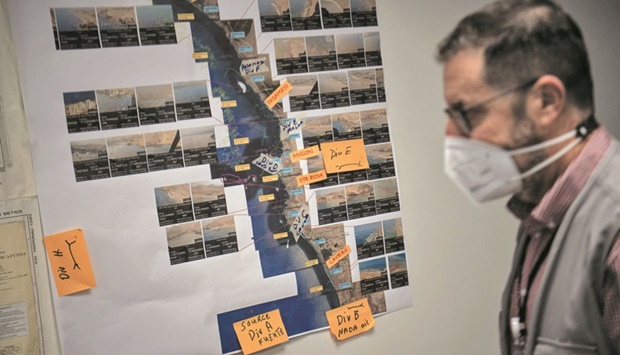 A Repsol staffer walks past pictures showing areas affected by the oil spill near the La Pampilla refinery in Callao, Peru.