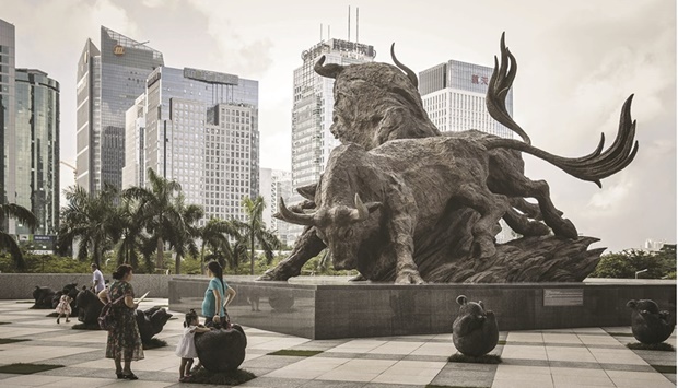 People stand in front of a sculpture of bulls at the entrance to the Shenzhen Stock Exchange building. Chinese shares look poised for mild early gains on their return from a week-long holiday, supported by a surge in Hong Kong-listed names and easing concerns about regulatory headwinds for the nationu2019s tech sector.
