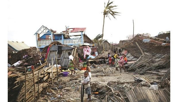 Locals stand among destroyed houses, in the aftermath of Cyclone Batsirai, in Mananjary, yesterday.