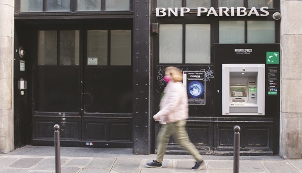 A pedestrian passes an automated teller machine at a BNP Paribas branch in Paris. BNP joined European peers in pledging higher profitability and bigger shareholder returns, while struggling to contain a surge in costs thatu2019s plaguing the industry.