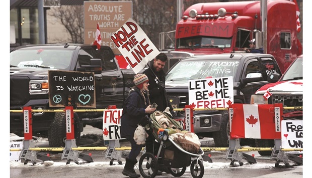 Protesters walk in front of parked trucks as demonstrators continue to protest the vaccine mandates implemented by Prime Minister Justin Trudeau in Ottawa, Canada, yesterday.