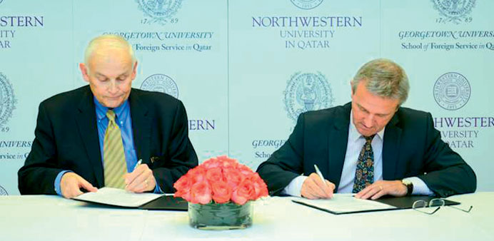 Officials from the two universities sign the agreement.