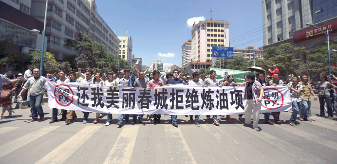   Demonstrators hold a banner as they marched yesterday during a protest against a planned refinery in Kunming, Yunnan province.