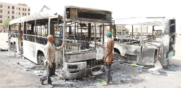 People inspect burnt-out buses following clashes in Khartoum on Thursday.