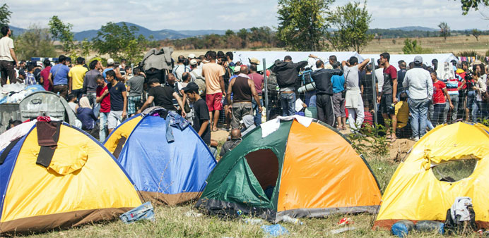 Migrants gather near tents after crossing the Serbian-Macedonia border