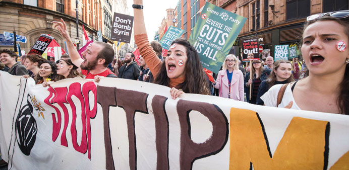 Demonstrators hold placards as they march through the streets of Manchester in protest against the Conservative government, on the first day of the an