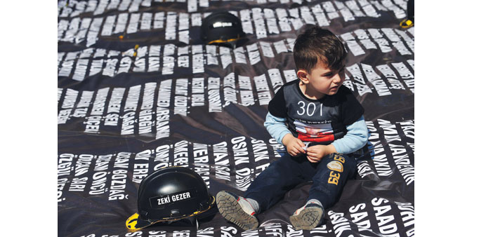 The child of a slain miner sits yesterday on a list, bearing the names of the 301 victims killed last year, at a special tribunal set up in a cultural