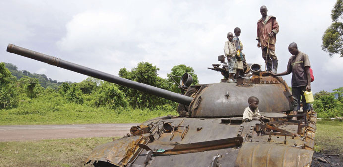    Congolese children play on a destroyed military tank, abandoned by M23 rebel fighters who surrendered in Kibumba yesterday.