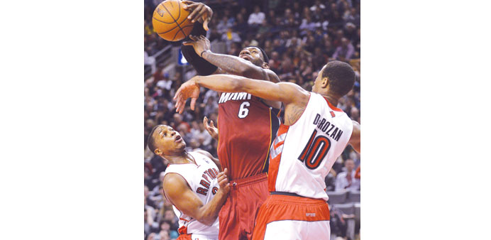 Miami Heatu2019s LeBron James (C) is fouled by Toronto Raptorsu2019 DeMar DeRozan (R) as Raptorsu2019 Kyle Lowry (L) looks on during the first half of their NBA b