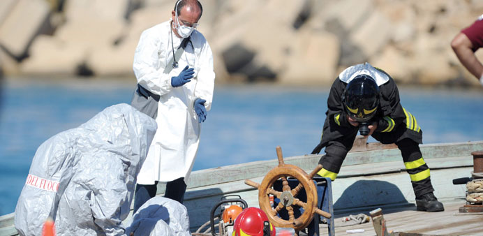 Fire fighters work yesterday on a boat in which 30 corpses were found two days ago during a rescue operation, in the port of Pozzallo, Sicily.