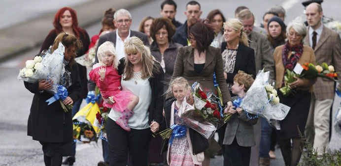Police officer Dave Phillipsu2019s wife Jennifer (front centre) and their children Abigail (front right) and Sophie lead mourners as they arrive to lay fl