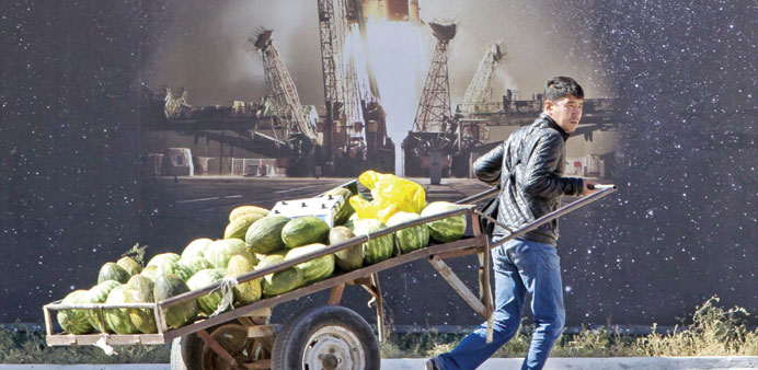 A man pulls a cart with watermelons in front of a poster of a Soyuz spacecraft in Baikonur, the town constructed to service the Baikonur cosmodrome.