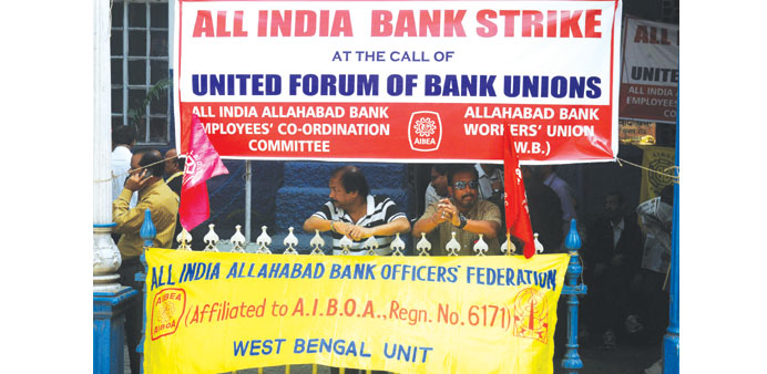 Employees stand near posters at the entrance of a bank during a strike in Kolkata yesterday.