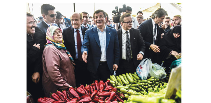 Turkish Prime Minister Ahmet Davutoglu (centre) gestures during a visit to a market as part of the election campaign in Istanbul yesterday.