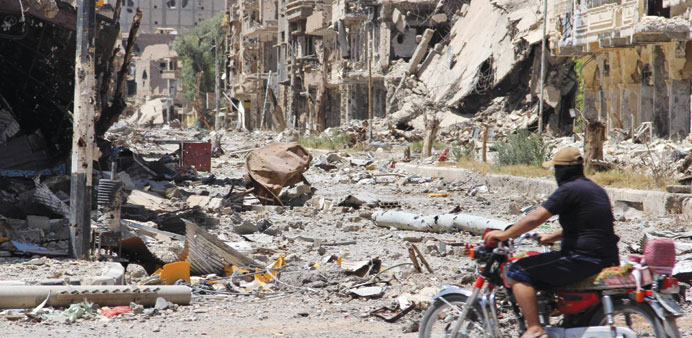 A Free Syrian Army fighter rides a motorcycle along a damaged street filled with debris in Deir al-Zor yesterday.