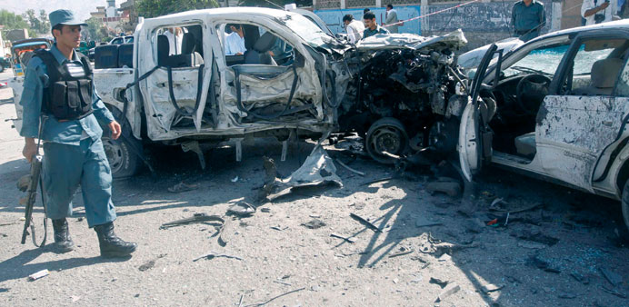 Afghan policemen inspect vehiclesu2019 wreckage at the site of a roadside bomb explosion in Jalalabad.