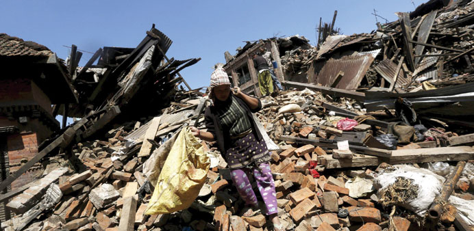 A woman carries her belongings as she walks over her collapsed house  in Bhaktapur, Nepal, yesterday.