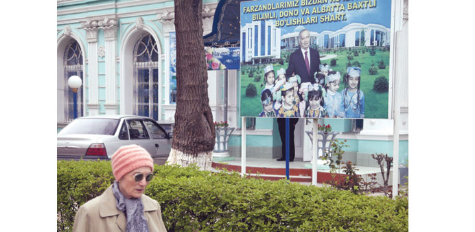A woman walks past an election board of Uzbekistanu2019s president Karimov near a polling station in Tashkent.