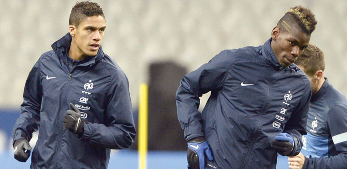 French national football teamu2019s defender Raphael Varane (L) and midfielder Paul Pogba run during a training session at the Stade de France in Saint-De