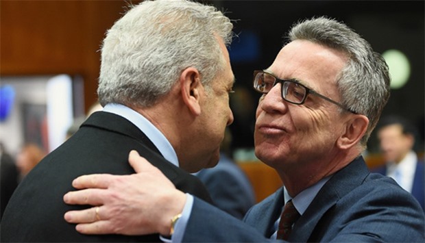 German Interior Minister Thomas de Maiziere (R) greets European Commissioner for Migration, Home Affairs and Citizenship Dimitris Avramopoulos