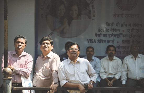 Bystanders watch share prices displayed on a digital broadcast on the facade of the Bombay Stock Exchange building in Mumbai. The S&P BSE Sensex closed up 95 points to 24,717.99 yesterday.