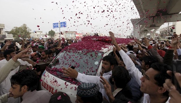 Supporters of Mumtaz Qadri shower rose petals on an ambulance carrying the body of Qadri for funeral in Rawalpindi on Tuesday.