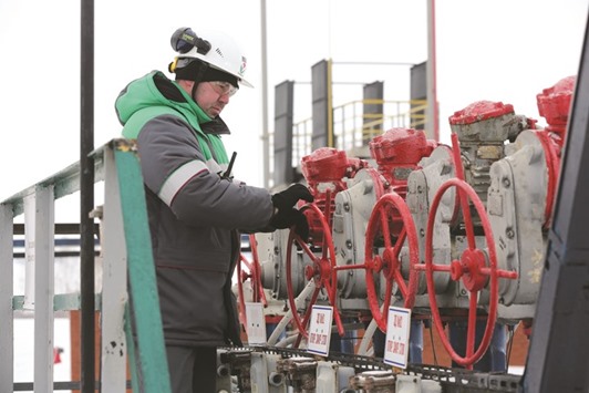 A worker turns a control wheel on pipes at an oil delivery point operated by Bashneft near Neftekamsk, Russia. There is a long way to go before oilu2019s supply and demand find a real balance, probably in 2017, the IEA said in its report.