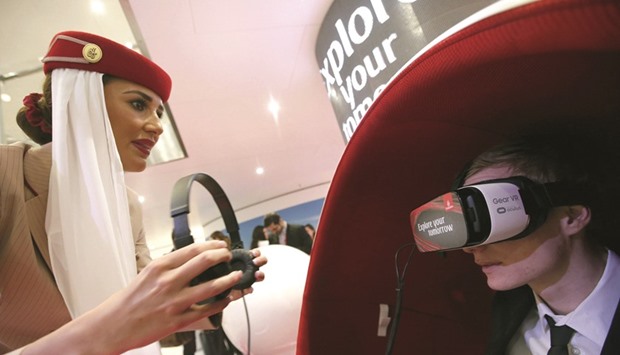An Emirates Airlines flight attendant assists a visitor using a Gear VR virtual reality headset by Oculus and Samsung Electronics, at the Emirates Airlines exhibition stand during the International Tourism Trade Fair (ITB) in Berlin on Wednesday.
