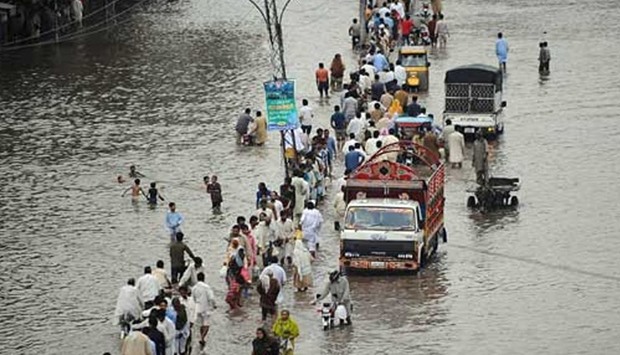 Pakistani commuters travel through a flooded street