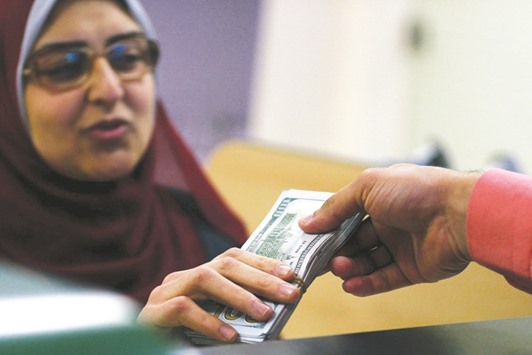An employee of a money changer hands US dollar notes to a customer at a bank in Cairo on Thursday. Egyptu2019s black market has flourished since the 2011 u201cArab Springu201d uprising scared off tourists and foreign investors, leading to shortages of the dollars they brought to the countryu2019s official banking system.