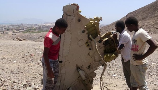 Boys hold a part of a United Arab Emirates Mirage plane that crashed in Aden on Monday