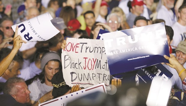 Trump supporters scramble to cover up a sign carried by a protester at a campaign rally on Sunday in Boca Raton, Florida.