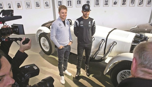 Mercedes drivers Nico Rosberg (left) and Lewis Hamilton pose in front of a Mercedes-Benz oldtimer racing car during a press conference in Fellbach, Germany, on Friday. (AFP)