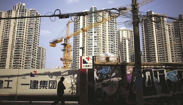 A man walks in front of a construction site in Shanghai. The weakening momentum seen in Chinau2019s industrial output, retail sales and property sector highlight scepticism about the Communist Partyu2019s goal of achieving average growth of 6.5%.