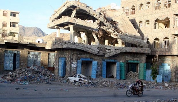 People ride a motorbike past a building destroyed during recent fighting in Yemen's southwestern city of Taiz.