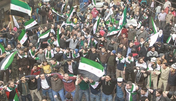 Civil defence members, rebel fighters and civilians carry opposition flags and chant slogans during a demonstration marking the fifth anniversary of the Syrian crisis in the old city of Aleppo.