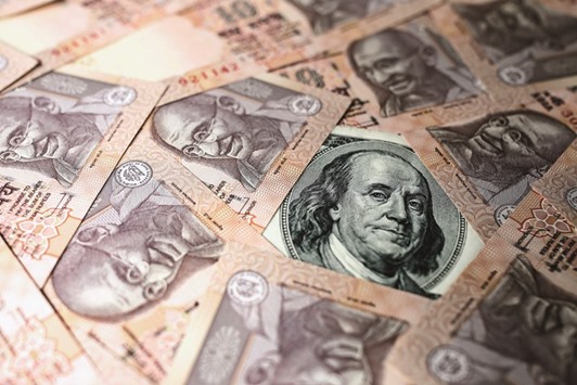 A US dollar bill and Indian rupee banknotes are arranged for a photograph in Mumbai. The rupee closed up 0.22% at 67.24 yesterday.