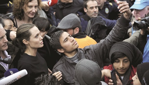 A migrant takes a selfie with Jolie during her visit at the port of Piraeus, near Athens.
