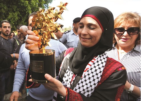 Hanan al-Hroub, a Palestinian teacher who won the $1mn Global Teacher award for her innovative approach of using play to counter violent behaviour poses with her prize during a public reception upon her arrival in the West Bank city of Jericho from Jordan yesterday. Hroub was awarded the Global Teacher award at a ceremony in Dubai on March 13.